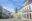 Wide cobblestone street lined with houses with large arched windows painted in pale pink, pistachio and pale blue