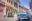 Vintage classic American car parked in street lined in two storey buildings painted in pastel colours