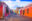 A wide, cobbled street in Antigua lined in brightly painted single-storey buildings - deep pink, blue, red, orange with a bright yellow arch connected the buildings at one end with a blue car driving down the middle of the road.