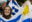 Girl with painted Uruguay flag on her cheek holding football flag with blue and white stripes and image of the sun